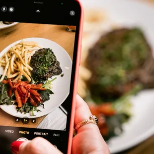 a person taking a picture of a plate of food