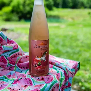 a bottle of watermelon wine on a picnic table