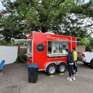 two people standing in front of a food truck