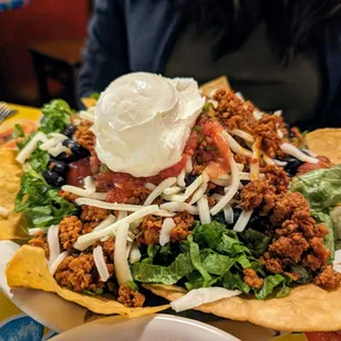 Tostada. $8.25. Black beans, crispy corn tortilla, lettuce, cheese, tomato, salsa fresca, sour cream, chips, chorizo (spicy pork sausage).