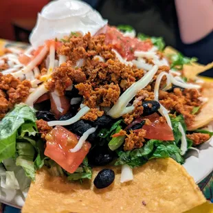 Tostada. $8.25. Black beans, crispy corn tortilla, lettuce, cheese, tomato, salsa fresca, sour cream, chips, chorizo (spicy pork sausage).