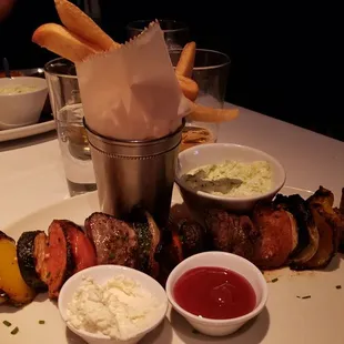 a platter of meat skewers and dips