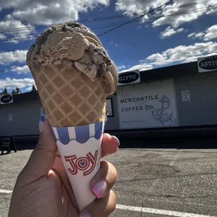 a hand holding a cone of ice cream