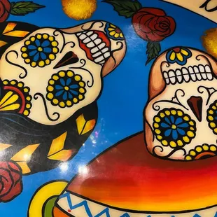 two sugar skulls with a banner above them