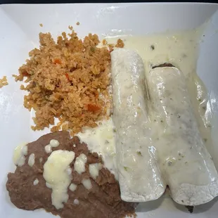 Enchiladas (one grilled chicken, one steak) in a cheese sauce with rice and beans