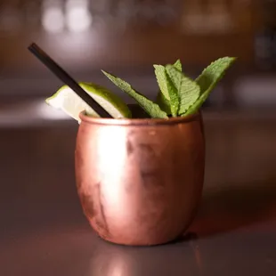 a copper cup with a garnish of lime and a straw in it