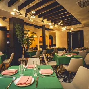 a dining room with green tablecloths and place settings