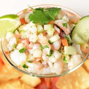 a bowl of salsa with chips and a cucumber