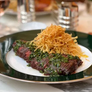 a plate of steak with cheese and chimica