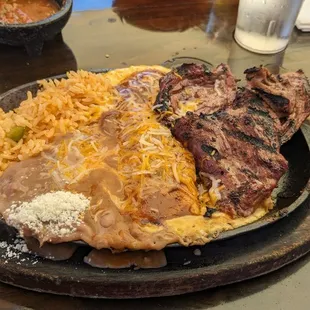 Steak and cheese enchilada with rice and beans