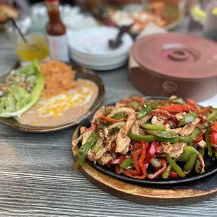 Chicken Fajitas eith tice and beans topped with cheese and guacamole.
