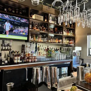 a bar with wine glasses and a television