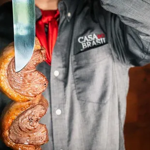 a man holding a sausage and a knife