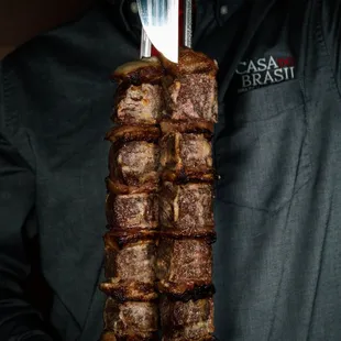 a man holding a fork and a meat skewer