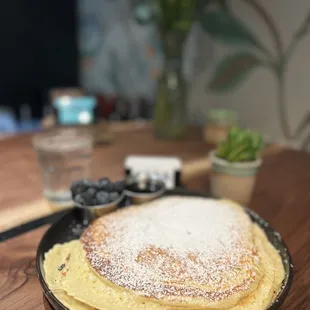 Plate size pancakes with a side of blueberries.