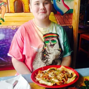 a boy sitting at a table with a plate of food