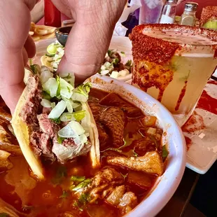 a person dipping a tortilla into a bowl of soup