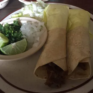 Barbaquoa tacos with a side of onions and cilantro and lime and a salad.