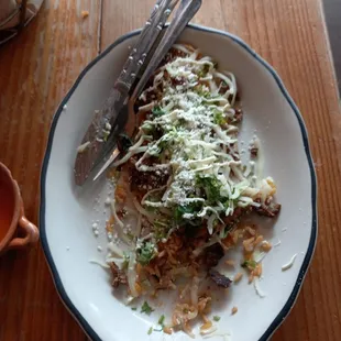 El huarache - a thick, oblong corn tortilla topped with beans, rice, onions, cilantro, cotija, crema and fajita meat.