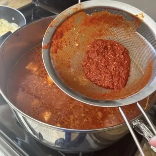 a person stirring a sauce in a pan