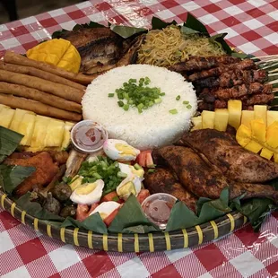 Bilao meal: pork bbq sticks, lumpia, pancit, eggplant, tomato &amp; salted egg, pork tocino, fbangus, mango, spineapple, rice, chicken