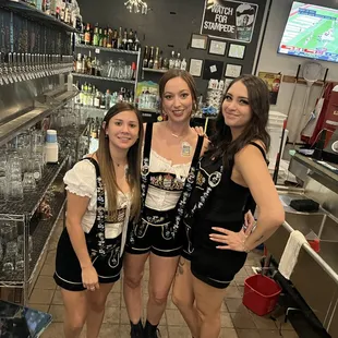 three women standing in front of a bar