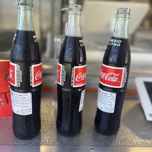 three bottles of coca cola on a table