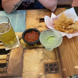 a man sitting at a table with chips and beer