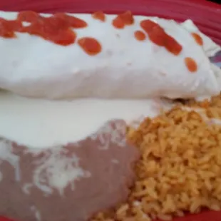 Chicken burrito topped with queso cheese and beans and rice.