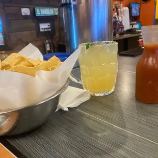 a bowl of chips and a drink on a bar