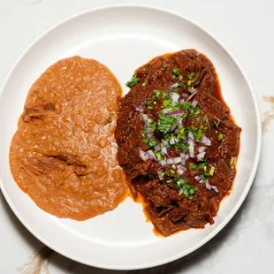 Birria plate.
House made tender marinated beef with cilantro, onions and lime on the side, served with refried beans and tortillas.