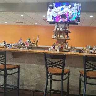 a bar with three chairs and a flat screen tv