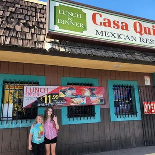 two girls standing in front of a restaurant