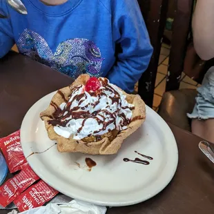 a young girl sitting at a table with a plate of food