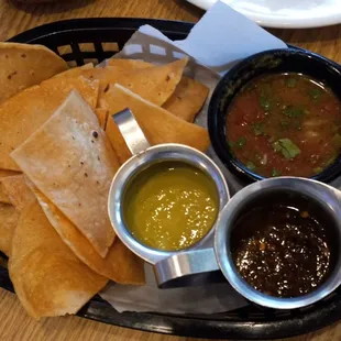 A spicy salsa verde, roasted pepper tomato and onion salsa, and fresh tomato and cilantro salsa and fried flour chips