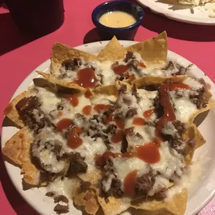 a plate of nachos with cheese and sauce
