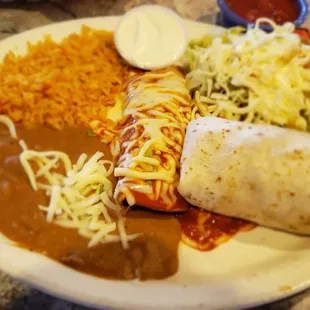 Combination plate with Al pastor enchilada, carnitas burrito, ground beet tostada, sour cream, rice and beans