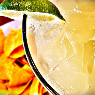 a margarita with a lime wedge and chips