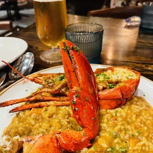 a plate of risoped lobster and rice with a glass of beer