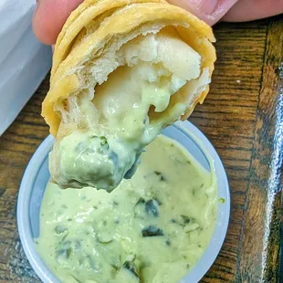a person dipping a sandwich into a bowl of guacamole