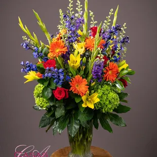 Vibrant vase of gerbera daisies, lilies, gladiolas, larkspur and roses.
