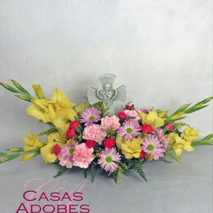 Cross keeps sake with a peaceful angel in a garden of spring flowers.