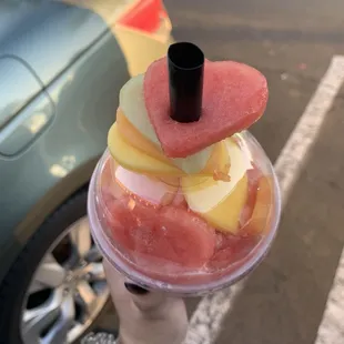 a hand holding a cup of fruit