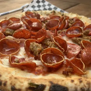 a pepperoni pizza on a checkered plate