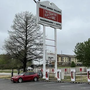 a red car parked in front of a sign