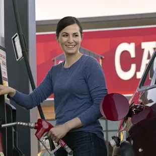 a woman pumping gas into her car