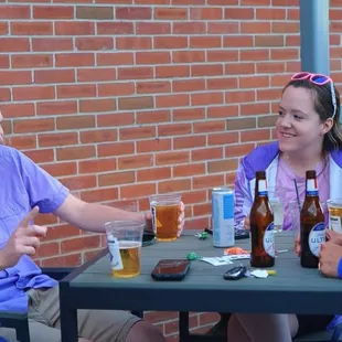 three women sitting at a table with beers