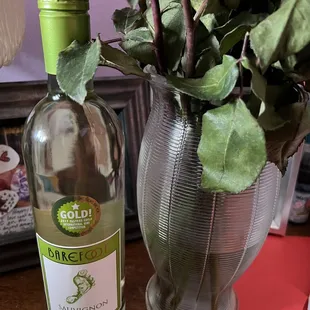 a bottle of wine next to a vase of flowers