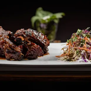 Grilled baby pork ribs marinated in house honey and spice BBQ sauce with Thai coleslaw. Tender, juicy, and yummy