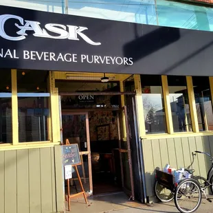Entrance from curb with cute bike display with boxes of different bottles of alcohol
